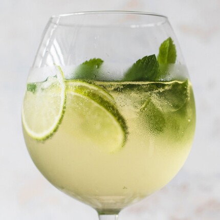 hugo elderflower spritz cocktail in a glass with mint and lime