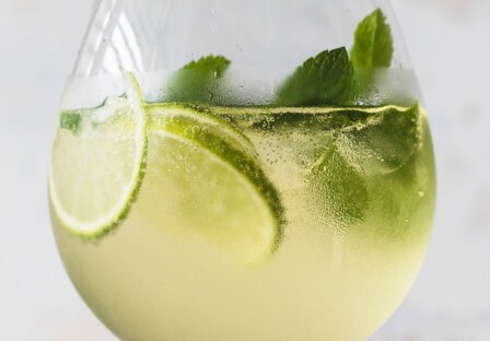 hugo elderflower spritz cocktail in a glass with mint and lime