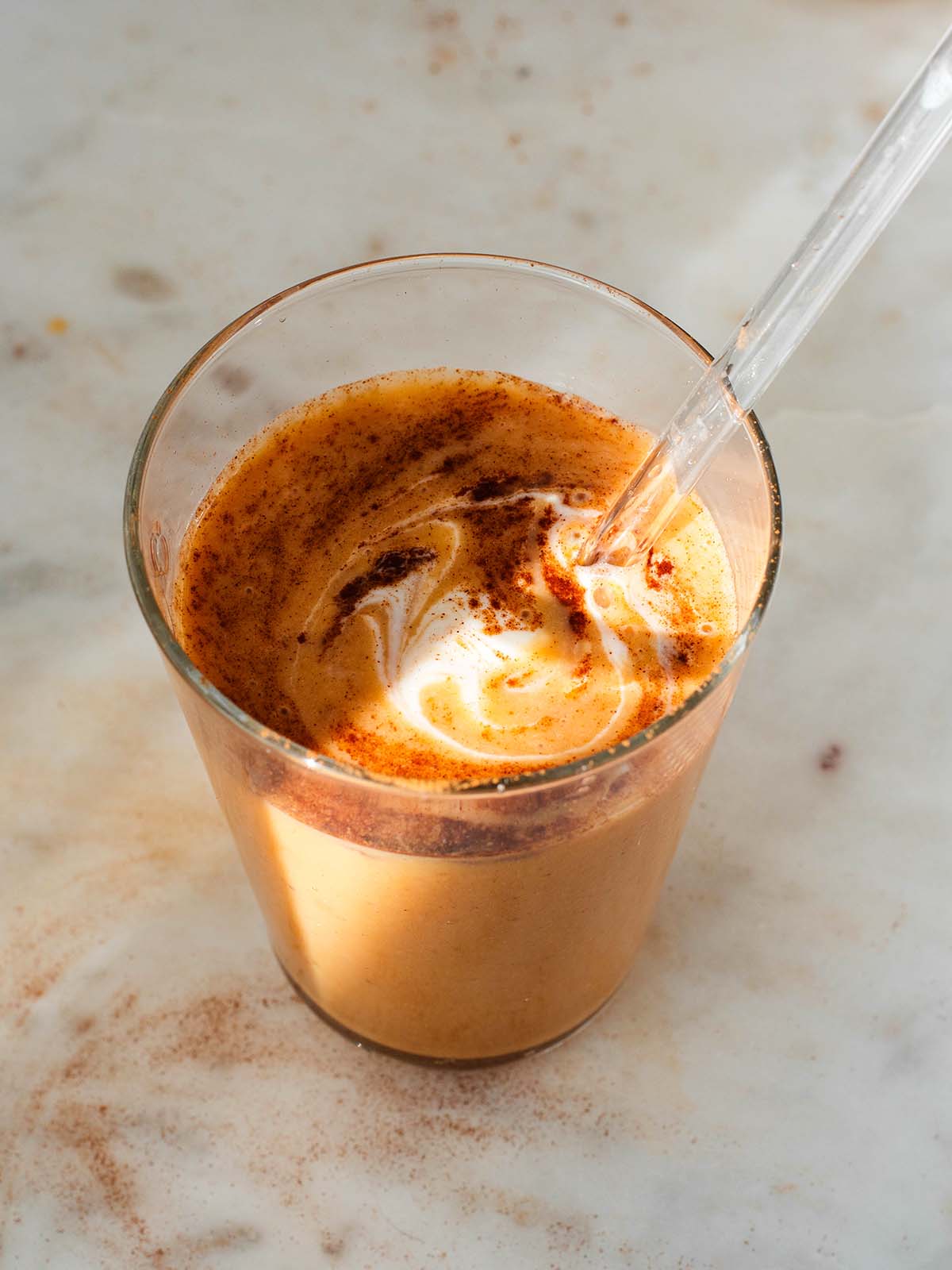 yogurt and cinnamon mixed into sweet potato smoothie with a straw